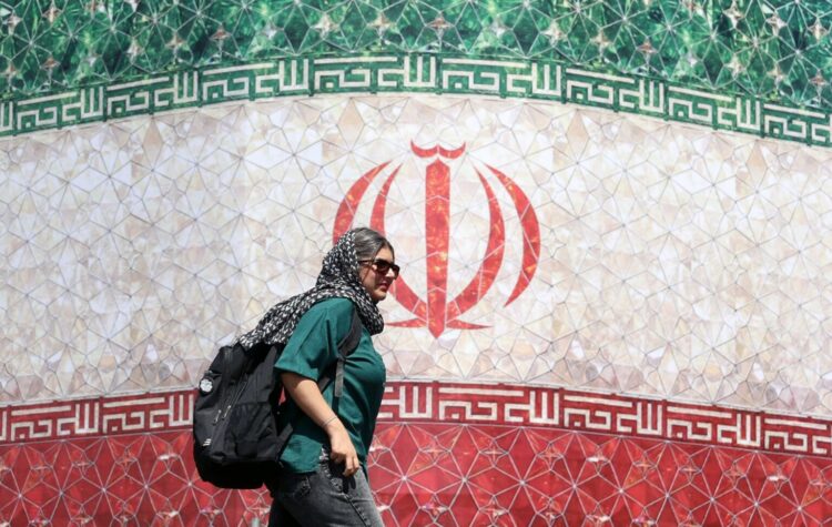 Una mujer iraní pasa junto a una valla publicitaria con la bandera nacional de Irán en la plaza Enqelab de Teherán, Irán. EFE/EPA/ABEDIN TAHERKENAREH. RESTRICCIONES: Prohibido el acceso a medios de comunicación israelíes/canales de televisión en persa fuera de Irán/Prohibido el acceso a BBC Persian/VOA Persian/Manoto TV/Televisión Internacional de Irán. (Según lo dispuesto por la Dirección General de Medios de Comunicación Extranjeros de Irán).