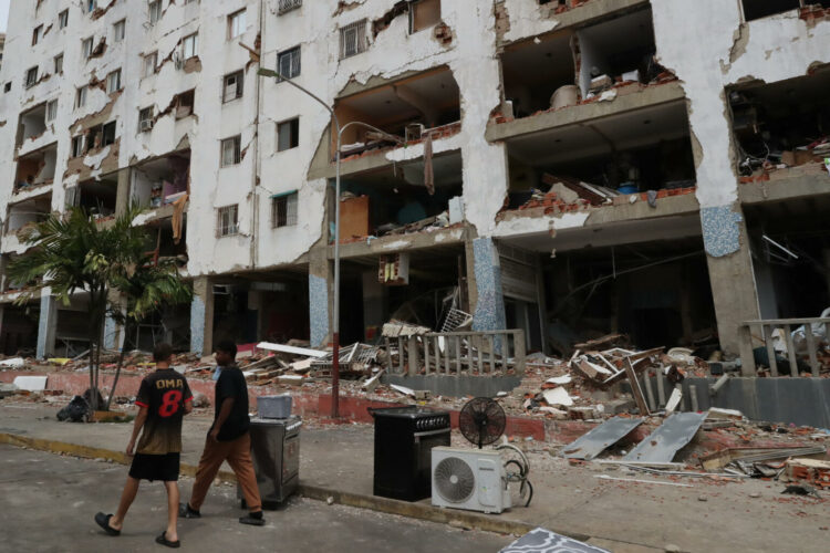 AME7428. LA GUAIRA (VENEZUELA), 04/07/2026.- Personas caminan este sábado frente a edificios afectados por los terremotos ocurridos en la zona de Caraballeda, en La Guaira (Venezuela). Venezuela evalúa los daños causados en las infraestructuras del país mientras intenta acelerar los trabajos de retirada de escombros cuando se cumplen diez días de los devastadores terremotos que causaron al menos 2.645 muertos, mientras las probabilidades de rescate de supervivientes se reducen al mínimo. EFE/ Raúl Martínez